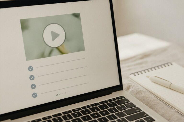 Laptop showing a video lesson with a play button and a list of lessons